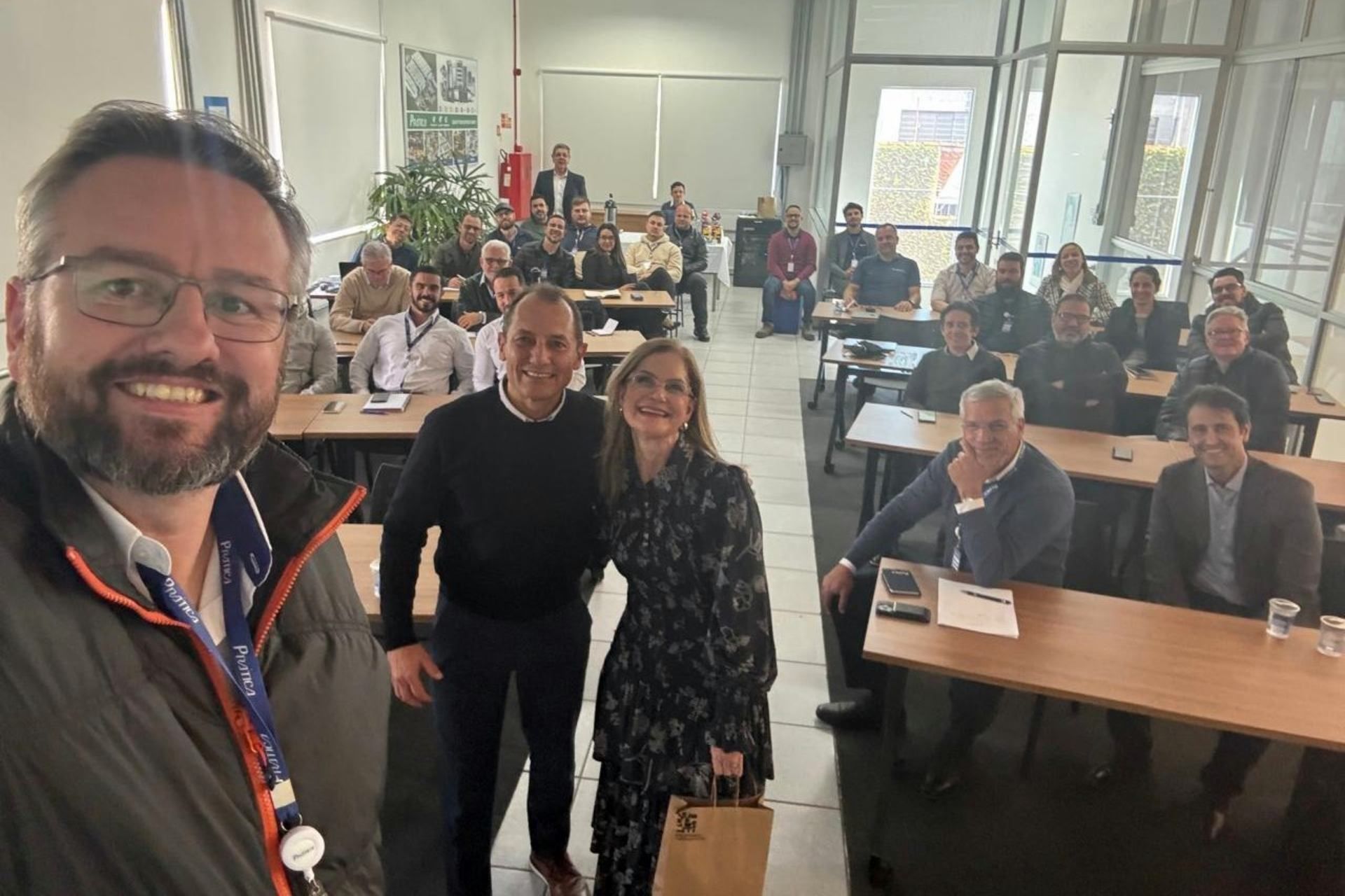 Um grupo de pessoas está posando para uma foto em uma sala de aula.