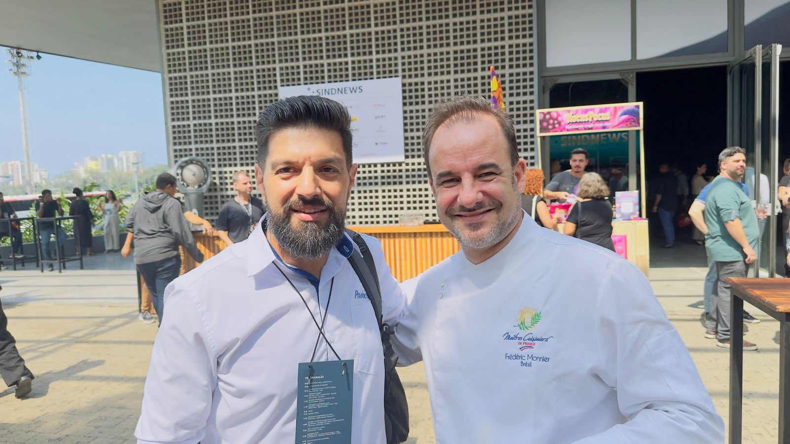 Dois homens estão posando para uma foto em frente a um prédio.