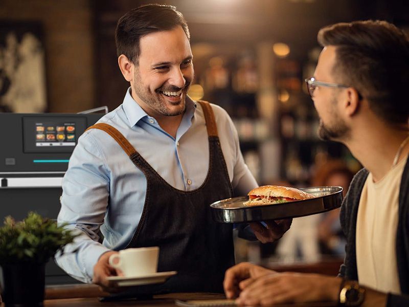 Um garçom está servindo um hambúrguer para um homem em um restaurante.