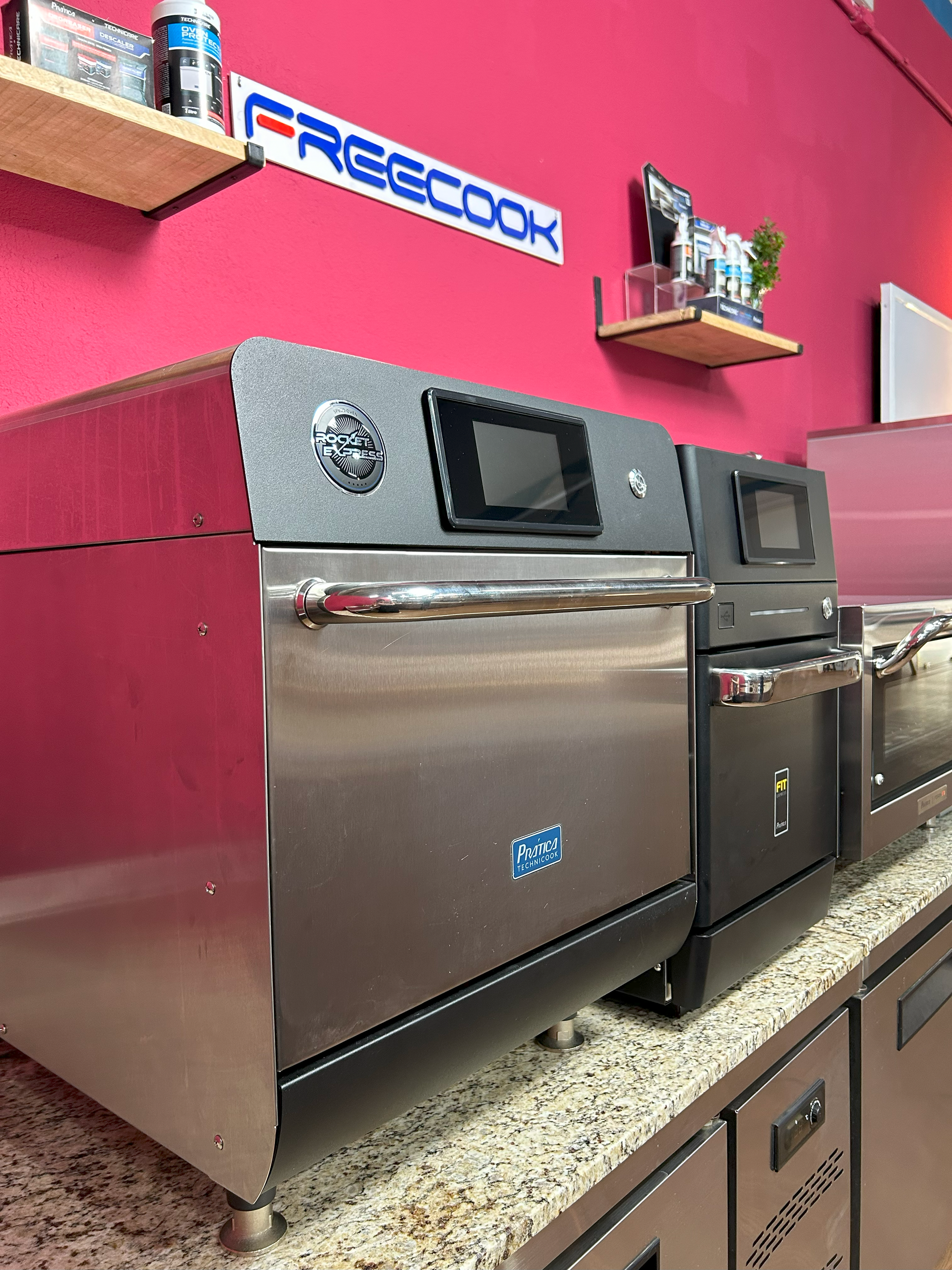 Uma fileira de fornos de aço inoxidável estão alinhados sobre um balcão.