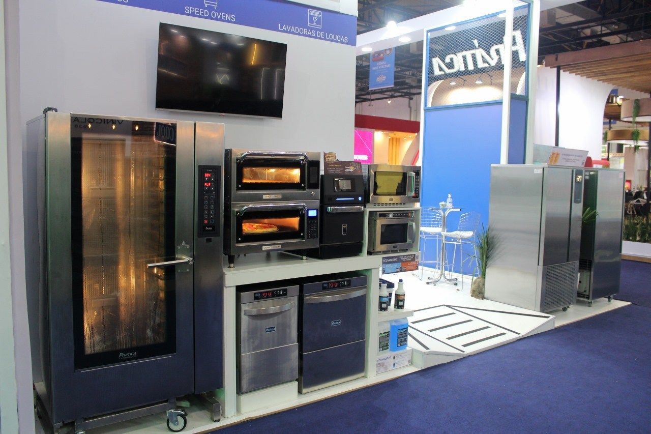 Uma exposição de fornos e micro-ondas de aço inoxidável em uma feira comercial.