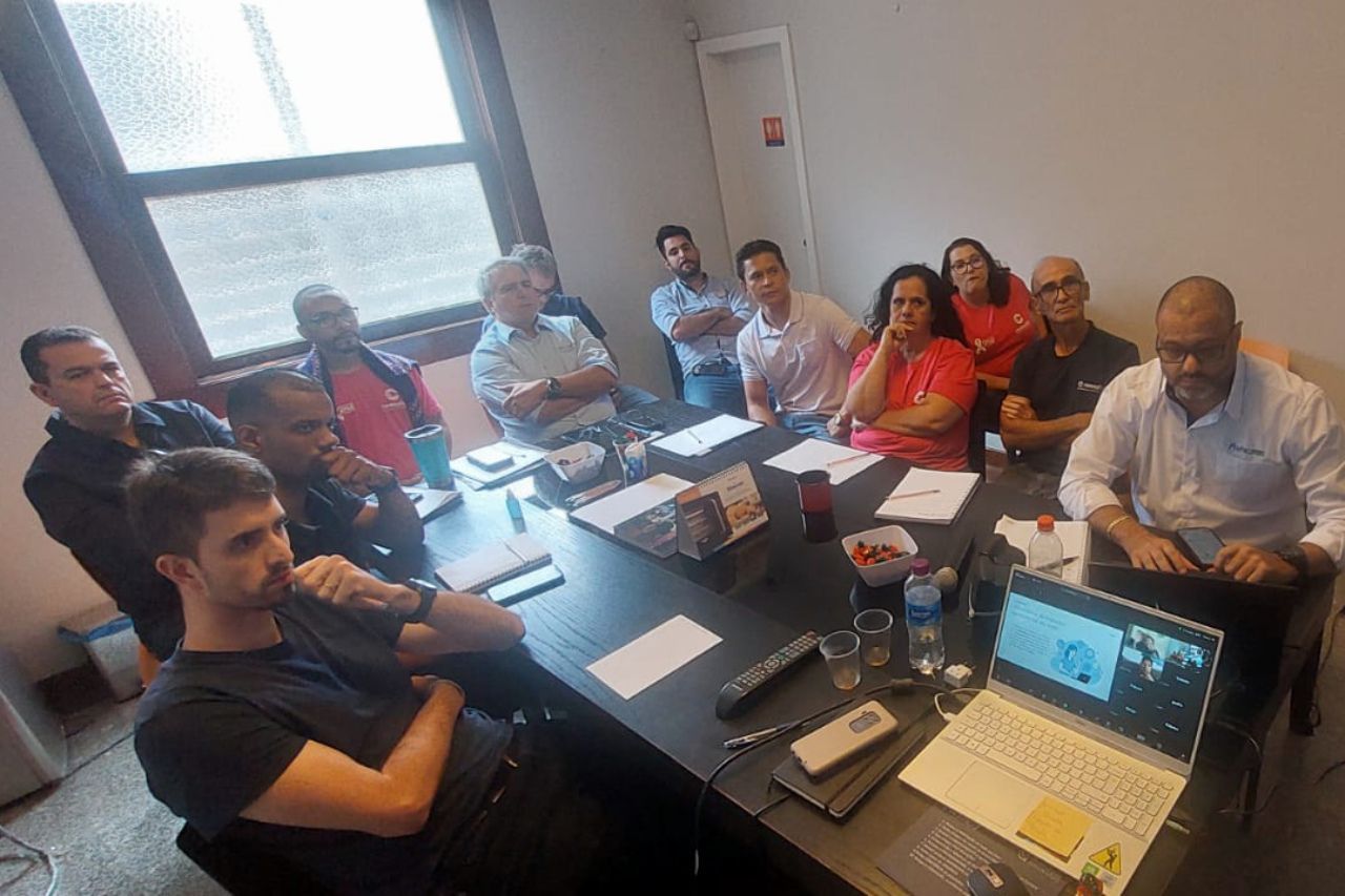 Um grupo de pessoas está sentado ao redor de uma mesa com laptops.
