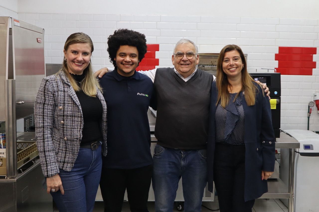 Um grupo de pessoas posa para uma foto em uma cozinha.