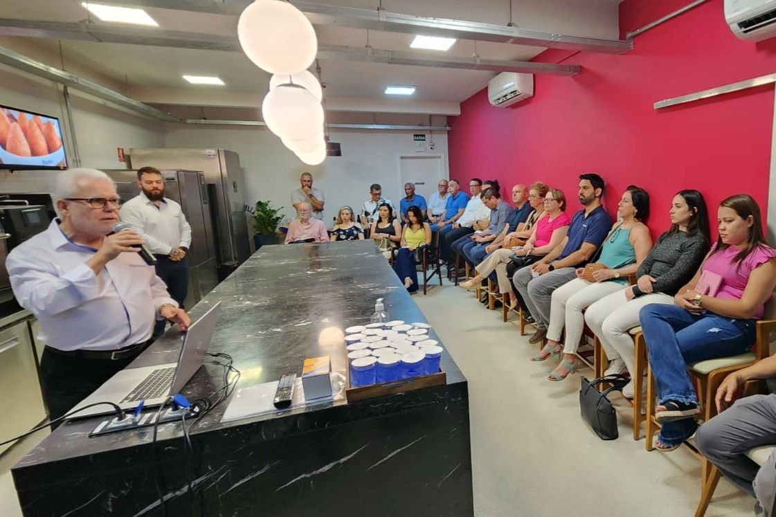 Um grupo de pessoas está sentado ao redor de uma mesa em uma sala.