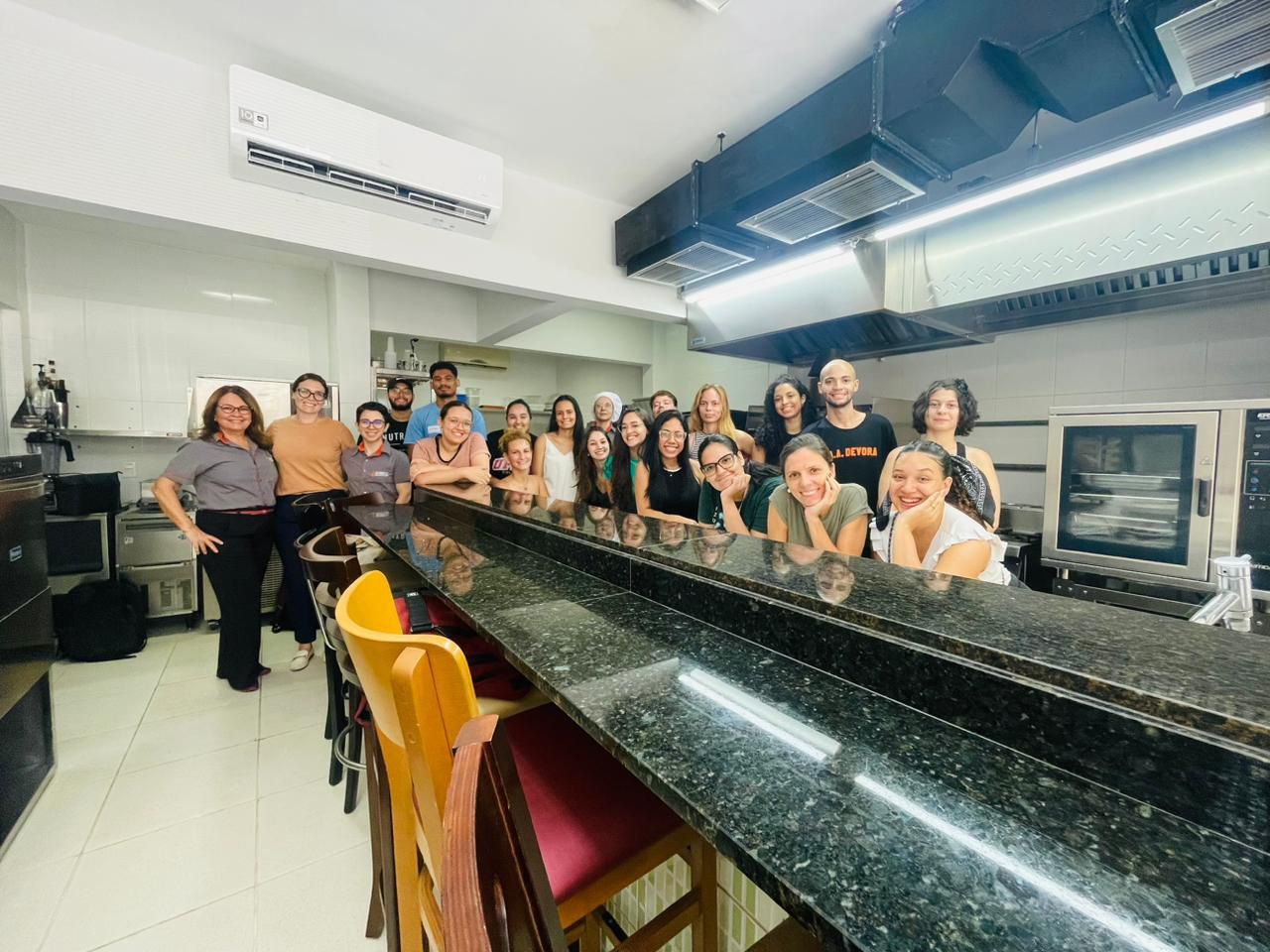 Um grupo de pessoas está posando para uma foto em uma cozinha.