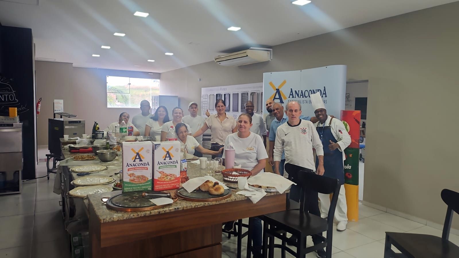 Um grupo de pessoas está em pé ao redor de uma mesa em uma sala.