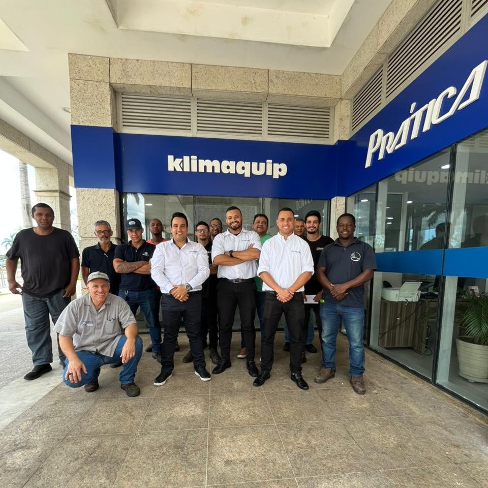 Um grupo de homens em pé em frente a um prédio que diz klimaquip