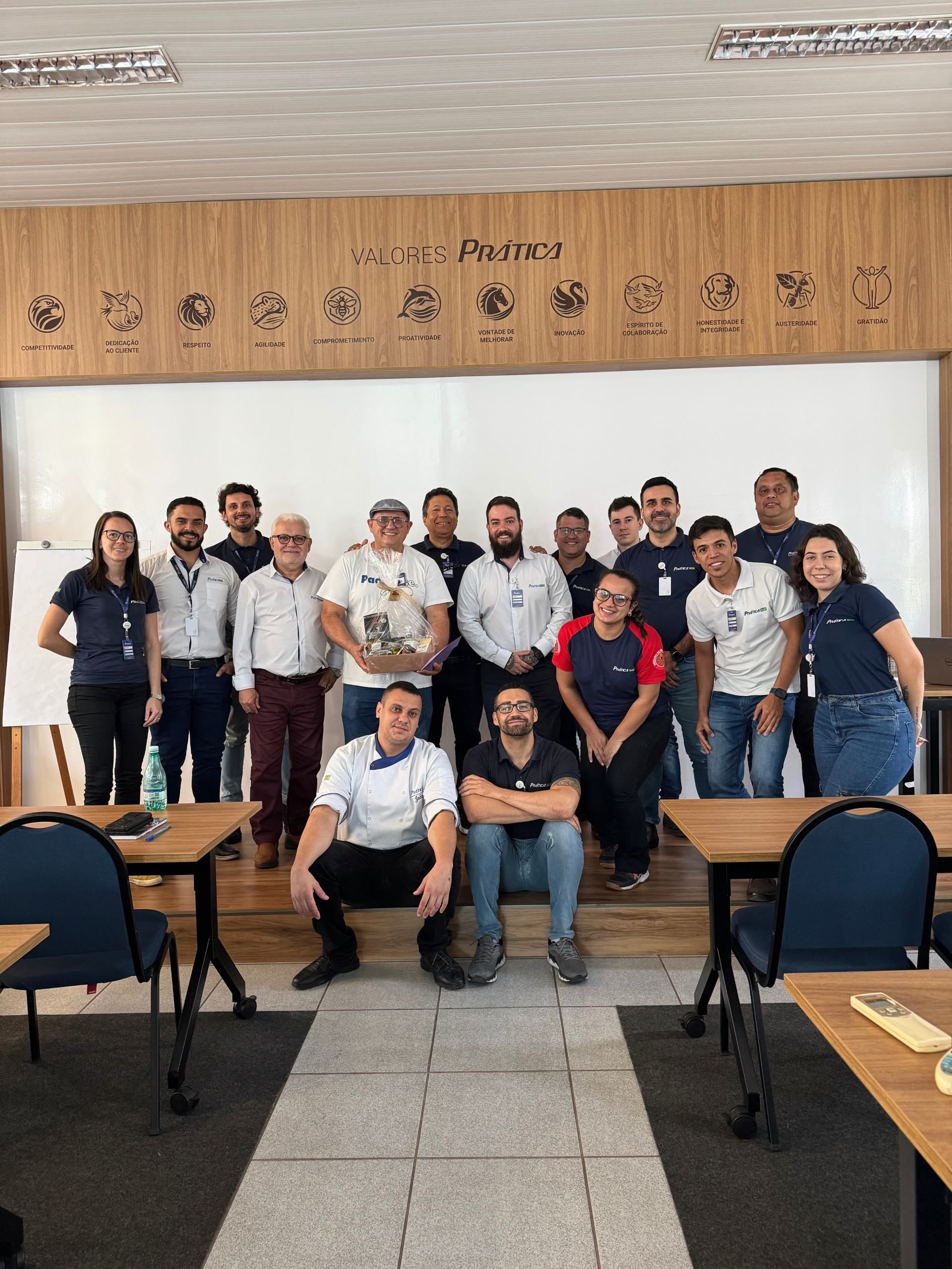 Um grupo de pessoas está posando para uma foto em uma sala de aula.