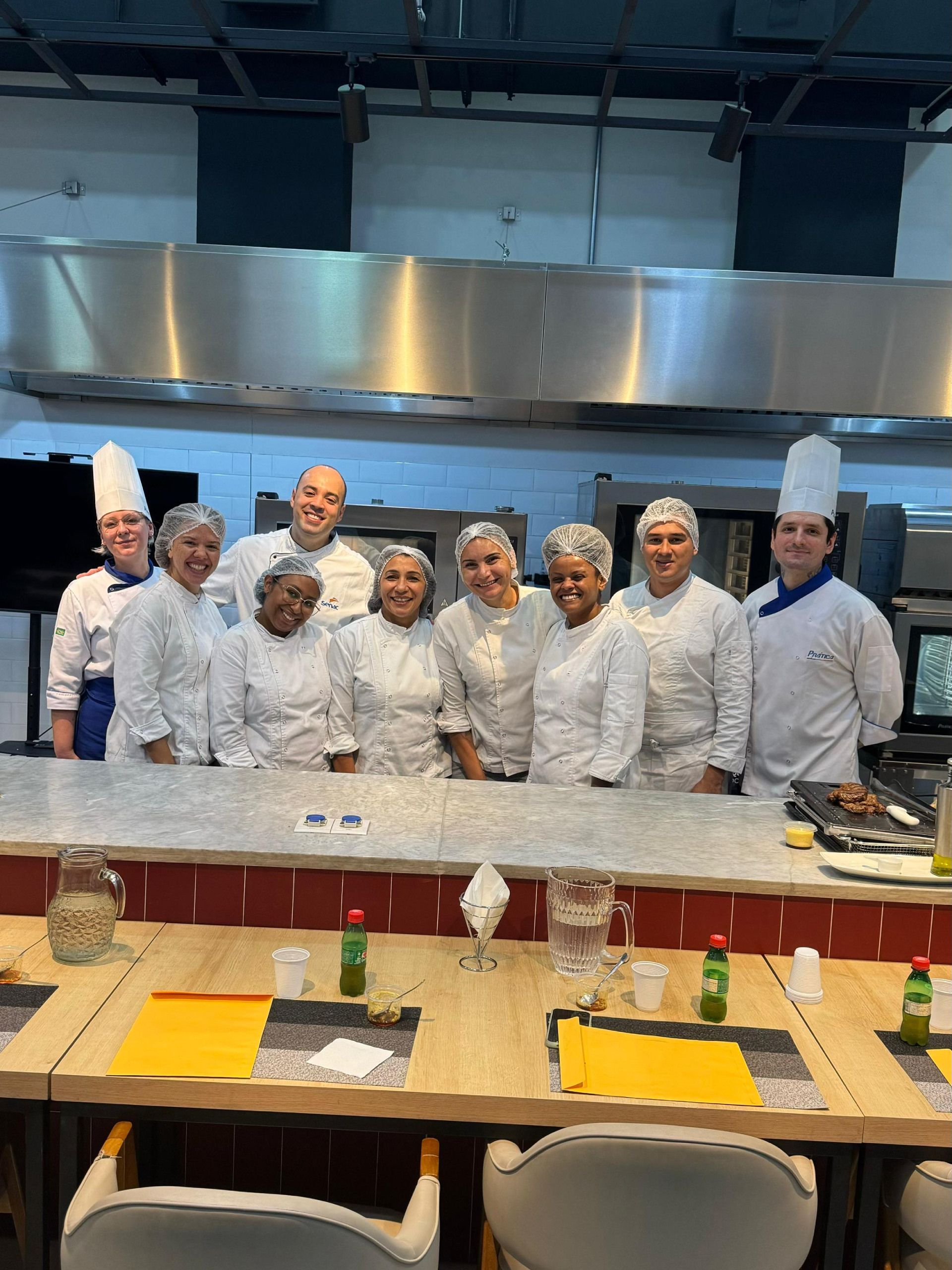 Um grupo de chefs está posando para uma foto em uma cozinha.