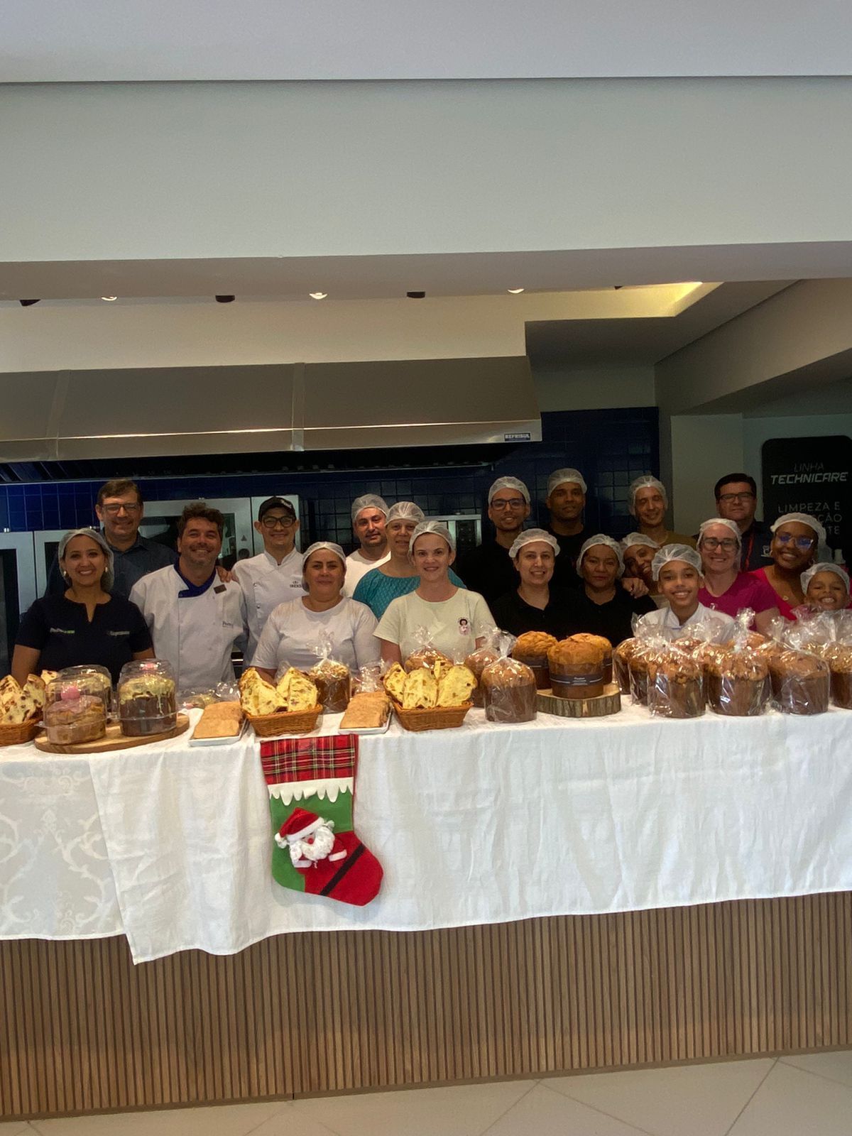 Um grupo de pessoas está posando para uma foto em frente a uma mesa cheia de comida.