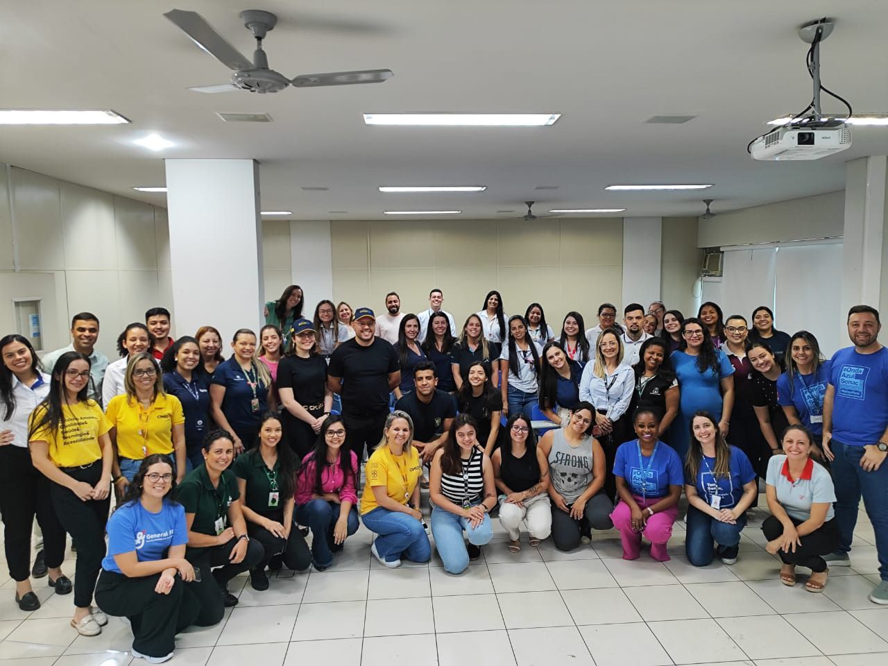 Um grande grupo de pessoas está posando para uma foto em uma sala.
