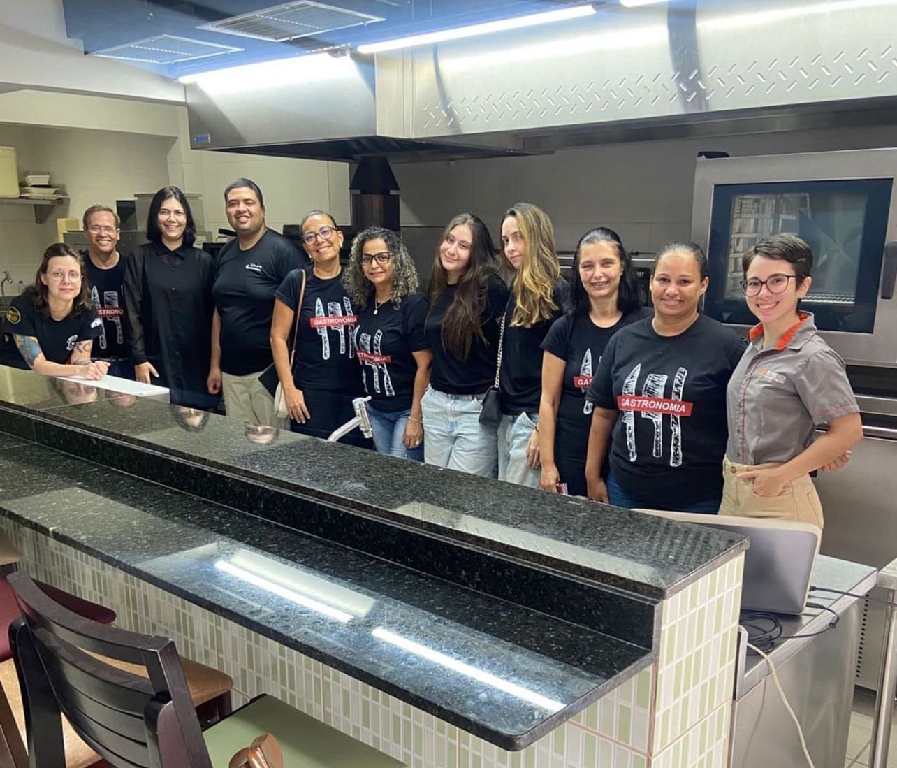 Um grupo de pessoas está posando para uma foto em uma cozinha.