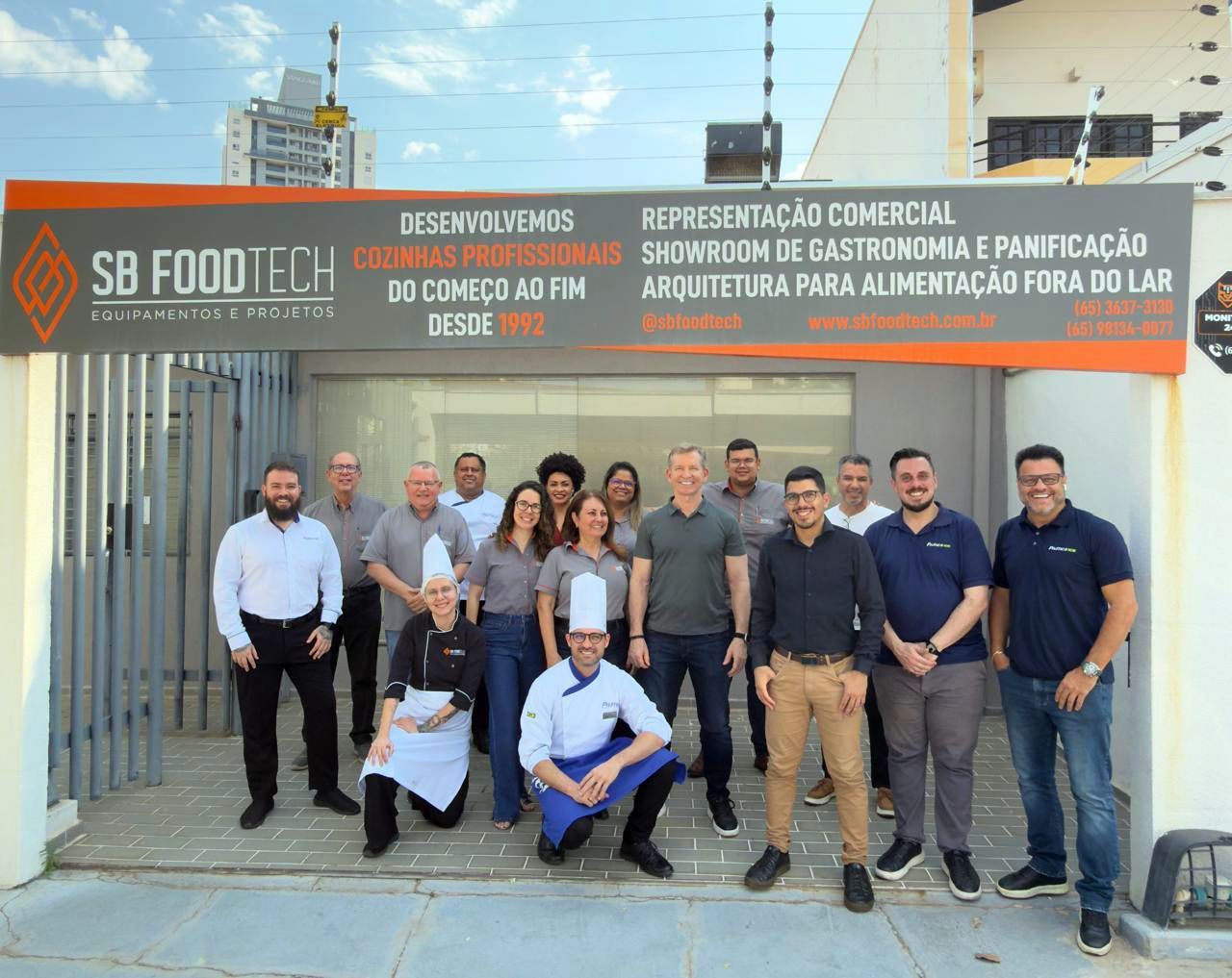 Um grupo de pessoas está posando para uma foto em uma cozinha.