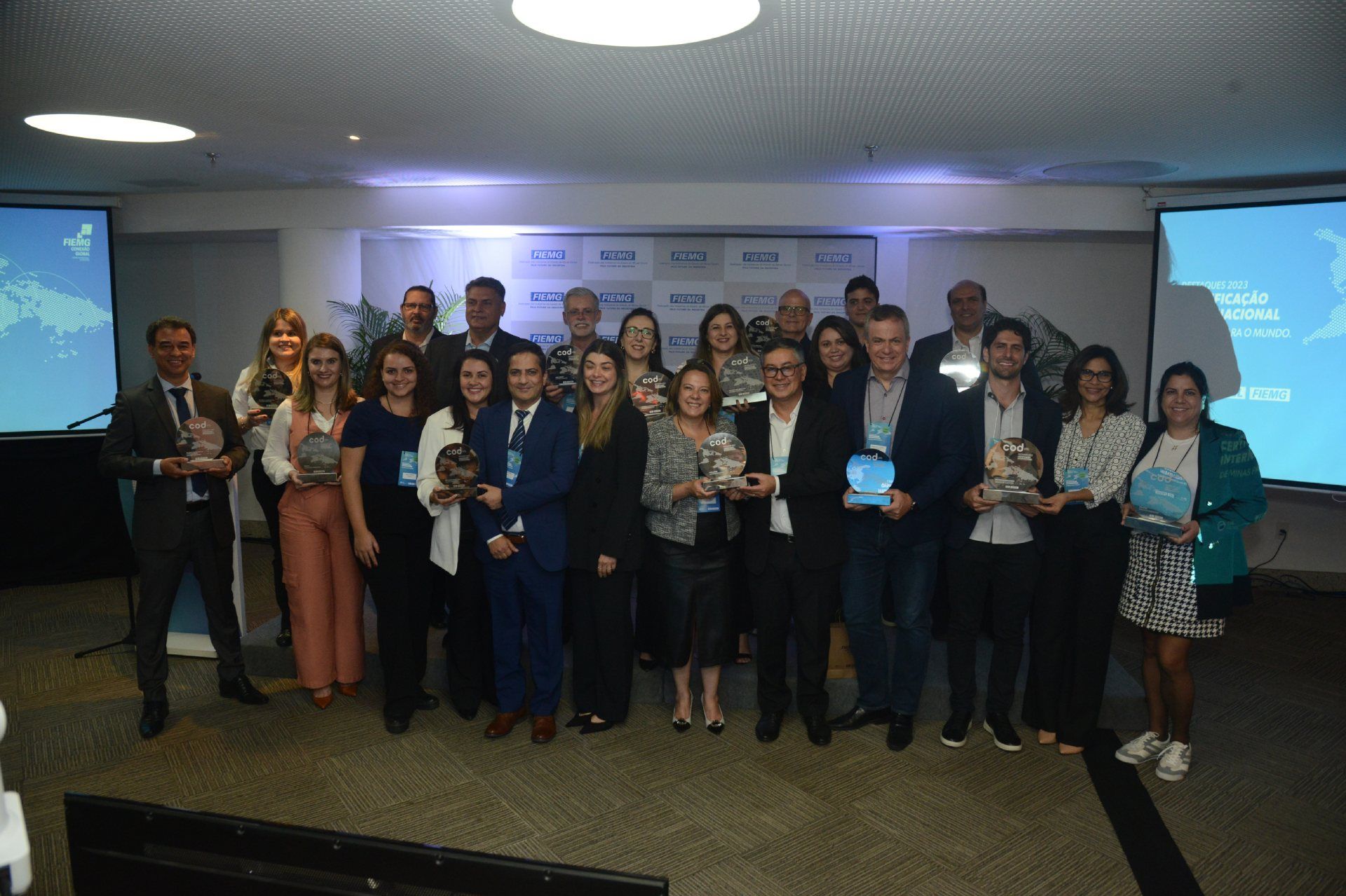 Um grupo de pessoas está em uma sala segurando prêmios.