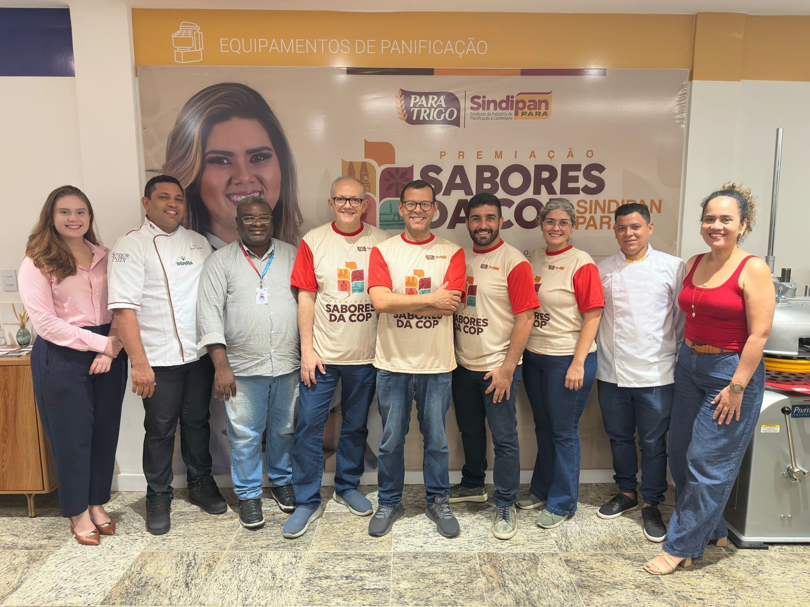 Um grupo de pessoas está posando para uma foto em uma cozinha.