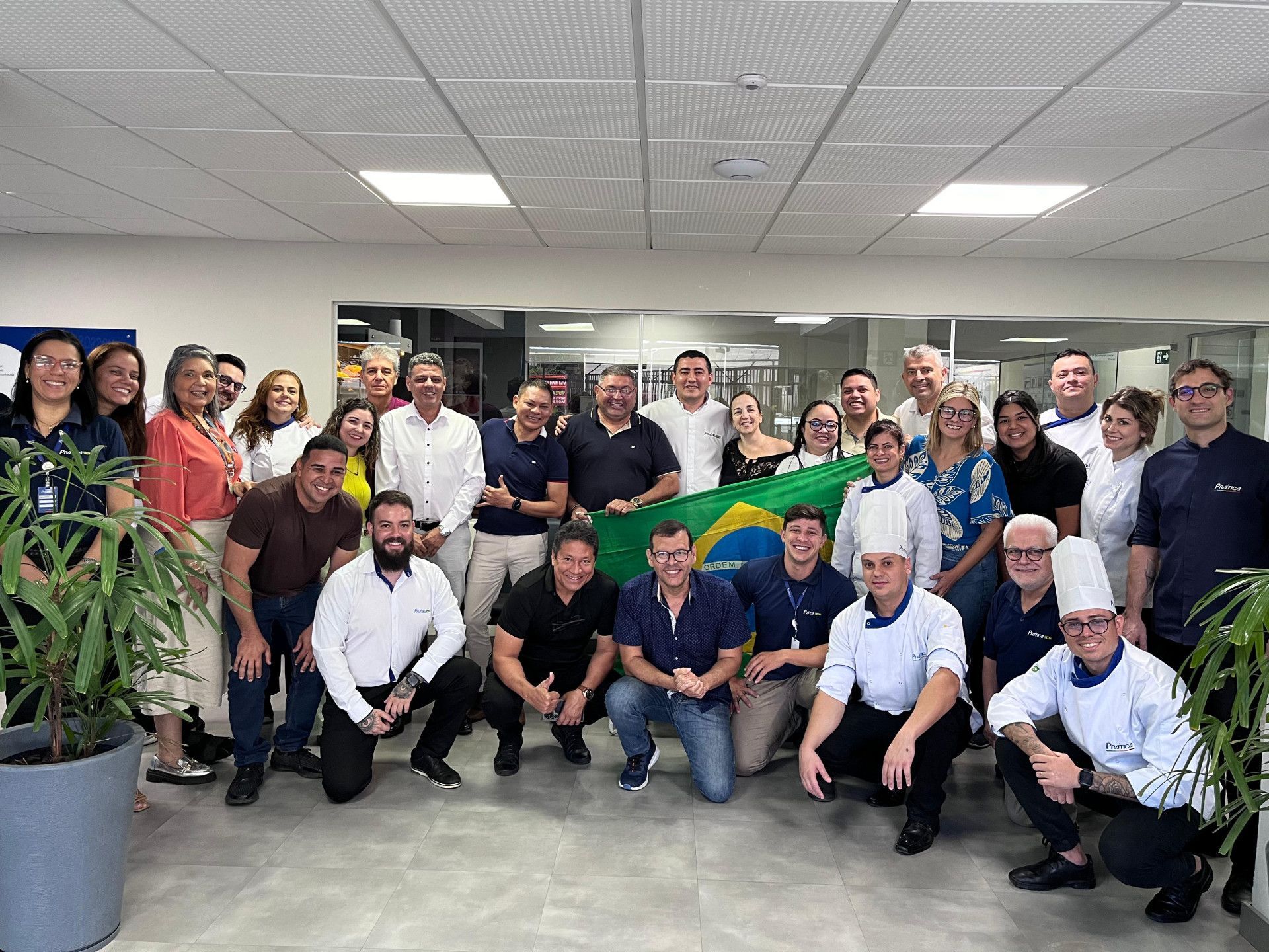 Um grande grupo de pessoas está posando para uma foto em uma sala.