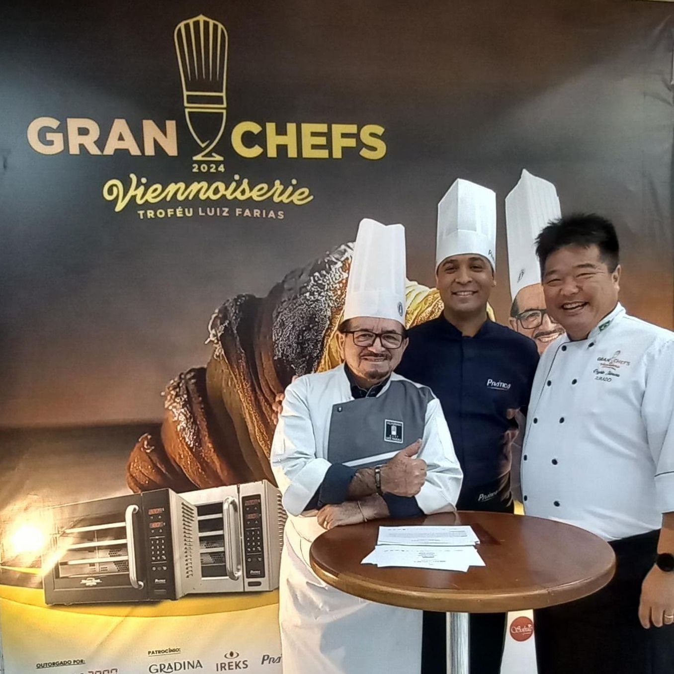 Um grupo de chefs em pé em frente a uma placa que diz gran chefs viennoiserie