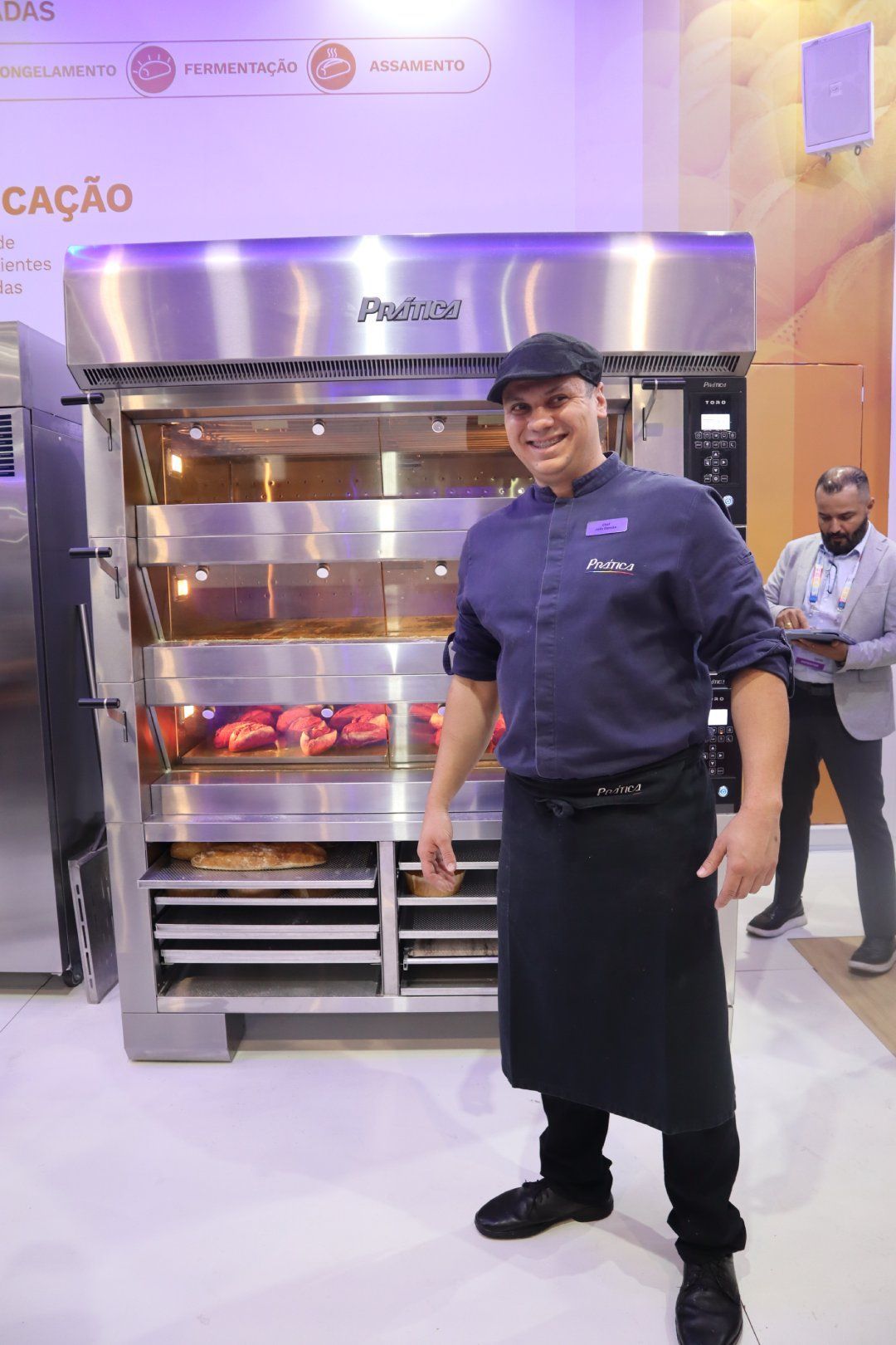 Um homem está em pé em frente a um forno de aço inoxidável.