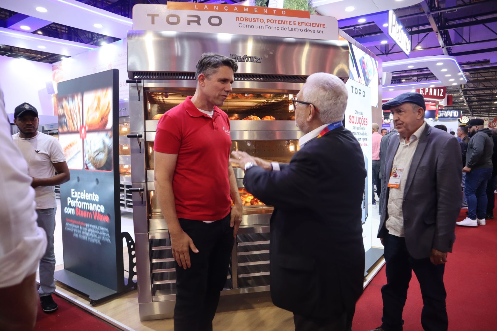 Um grupo de homens está em frente a um grande forno conversando entre si.