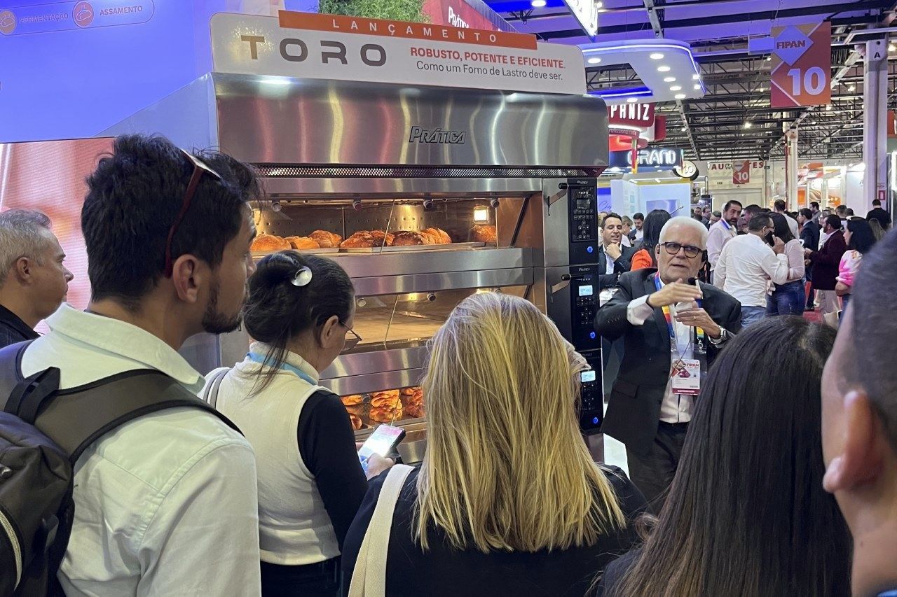 Um grupo de pessoas está em frente a um forno.