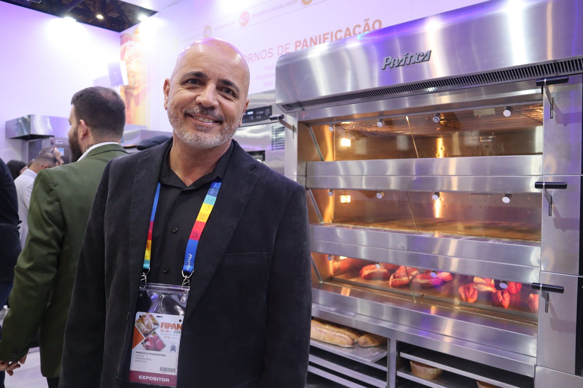 Um homem está em pé em frente a um grande forno de aço inoxidável.