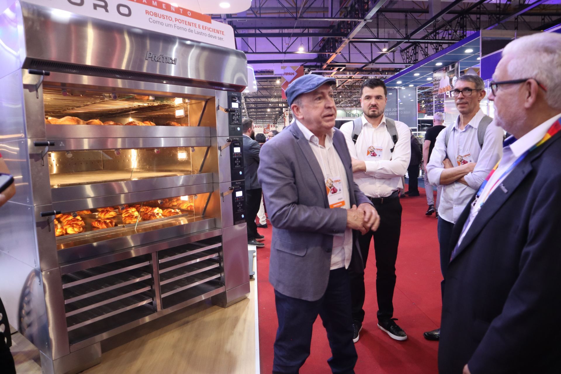 Um grupo de homens está em volta de um forno de aço inoxidável.