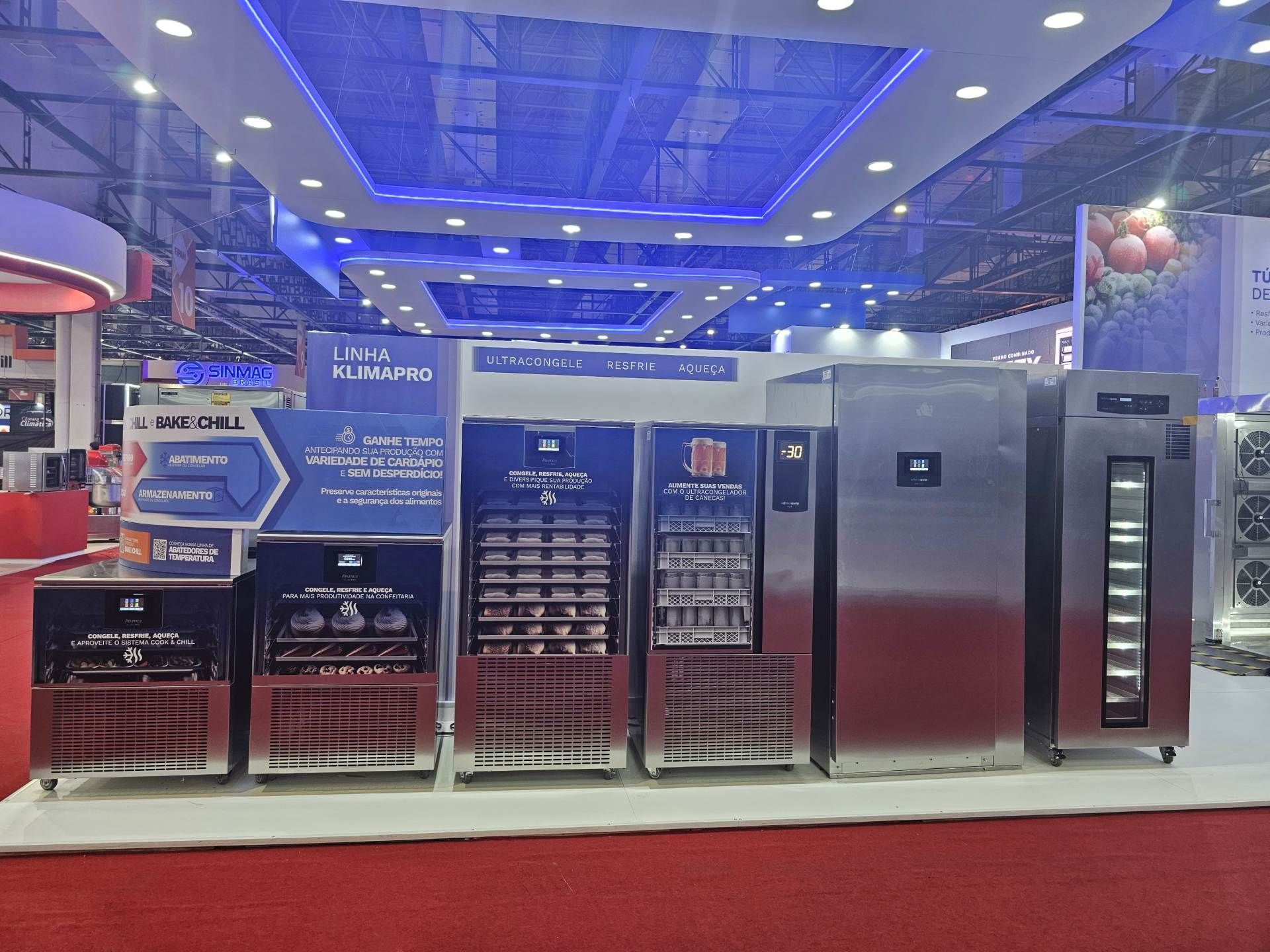 Uma fileira de geladeiras de aço inoxidável estão alinhadas em uma sala.