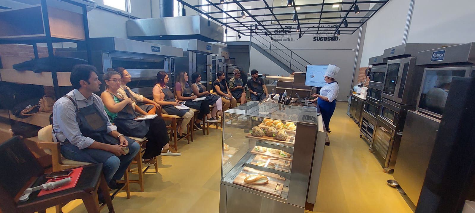 Um grupo de pessoas está sentado em cadeiras em uma padaria.