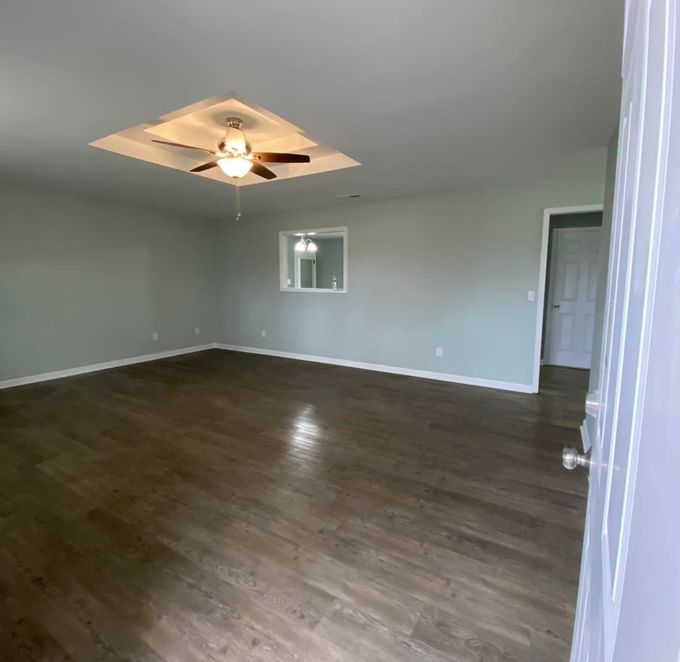 Empty room with wood floors, light blue walls, and a recessed ceiling with a ceiling fan.