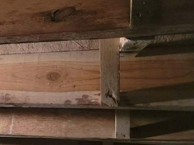 Wooden beams and planks, possibly in a basement or crawlspace, showing construction details.