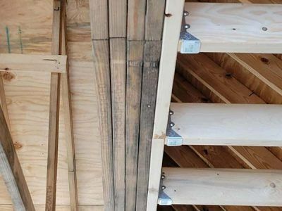 Wooden rafters and supports, some with metal brackets, inside of a building under construction.