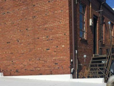 Red brick building exterior with a metal staircase and a window.