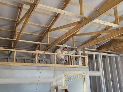 Construction worker in protective suit working on a wooden frame ceiling.