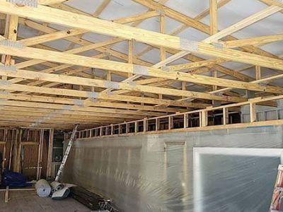 Wooden roof trusses under construction, over a room with a partially built wall.