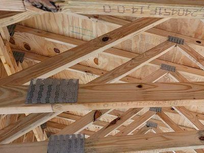 Wooden roof trusses with plywood sheathing, held together by metal connectors.