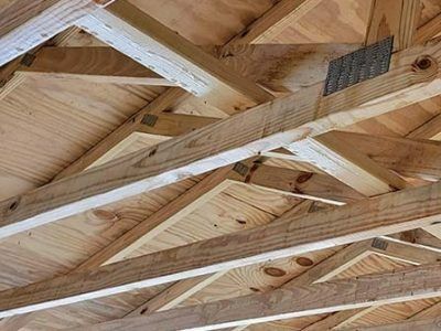 Wooden roof truss system, with plywood and angled beams, viewed from below.