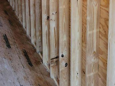Wooden stairway construction with vertical logs on the right and unfinished plywood on the left.