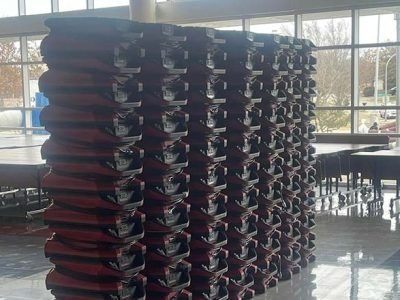 Stacked, red and black metal beams creating a wavy pattern, indoors by a large window.