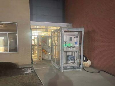 A large, industrial air handler is installed outside a building entrance, partially blocking the doorway.