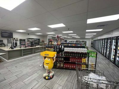 Interior of a well-lit convenience store with a variety of products, including beverages and snacks, and a checkout counter.
