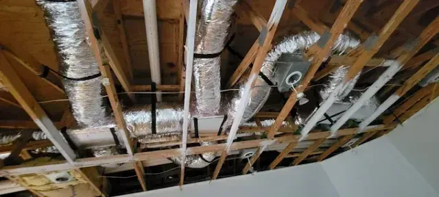 View of exposed ceiling joists with ductwork, piping, and wiring.