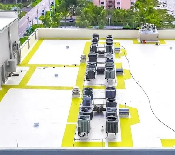 Overhead view of a flat roof with air conditioning units and yellow-painted walkways.