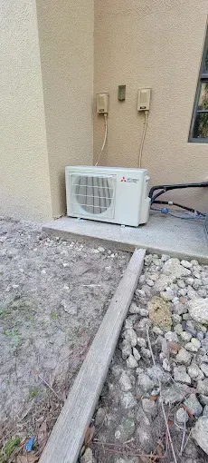 An outdoor air conditioning unit next to a building on a concrete pad.