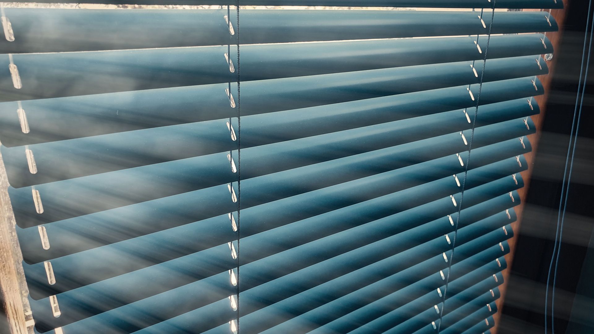 The sun is shining through the blinds of a window.