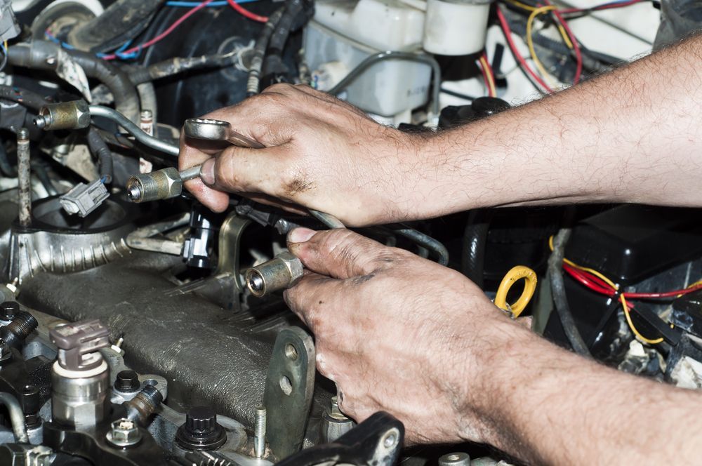 A Man is Working on a Car Engine With a Wrench — J & W Mechanical In Elermore Vale, NSW