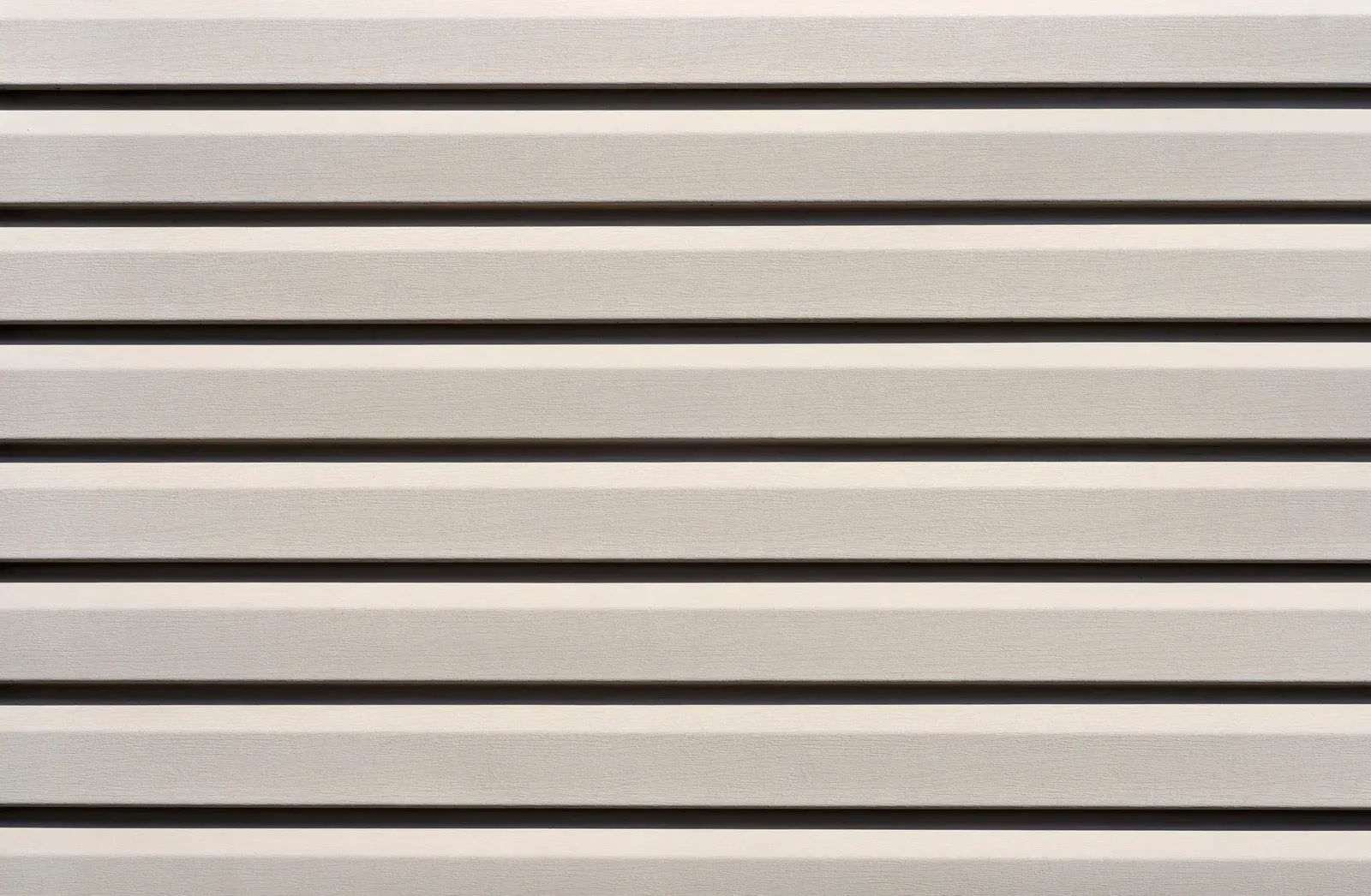 Horizontal, light-colored siding with dark shadow lines.