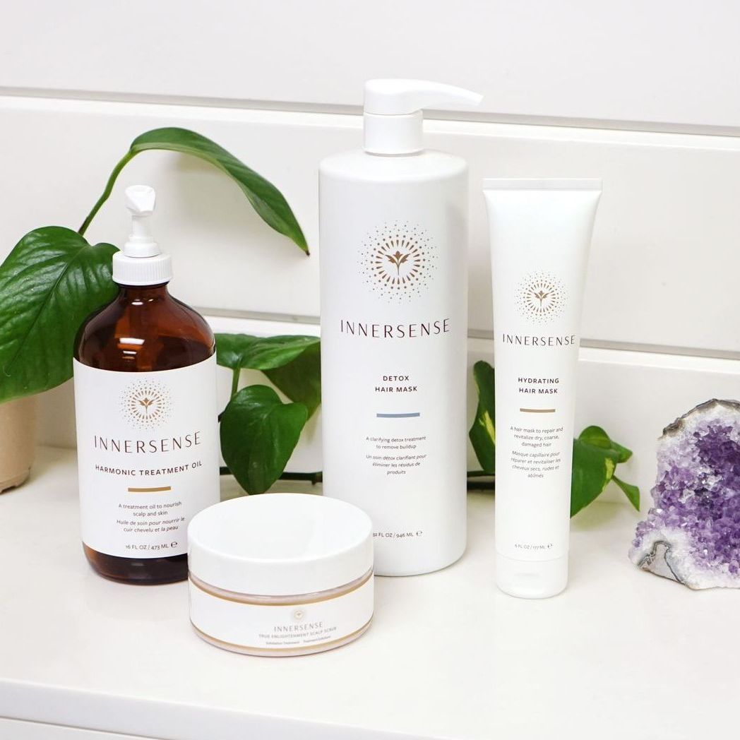 Three bottles of hair products are sitting on a counter next to a plant.