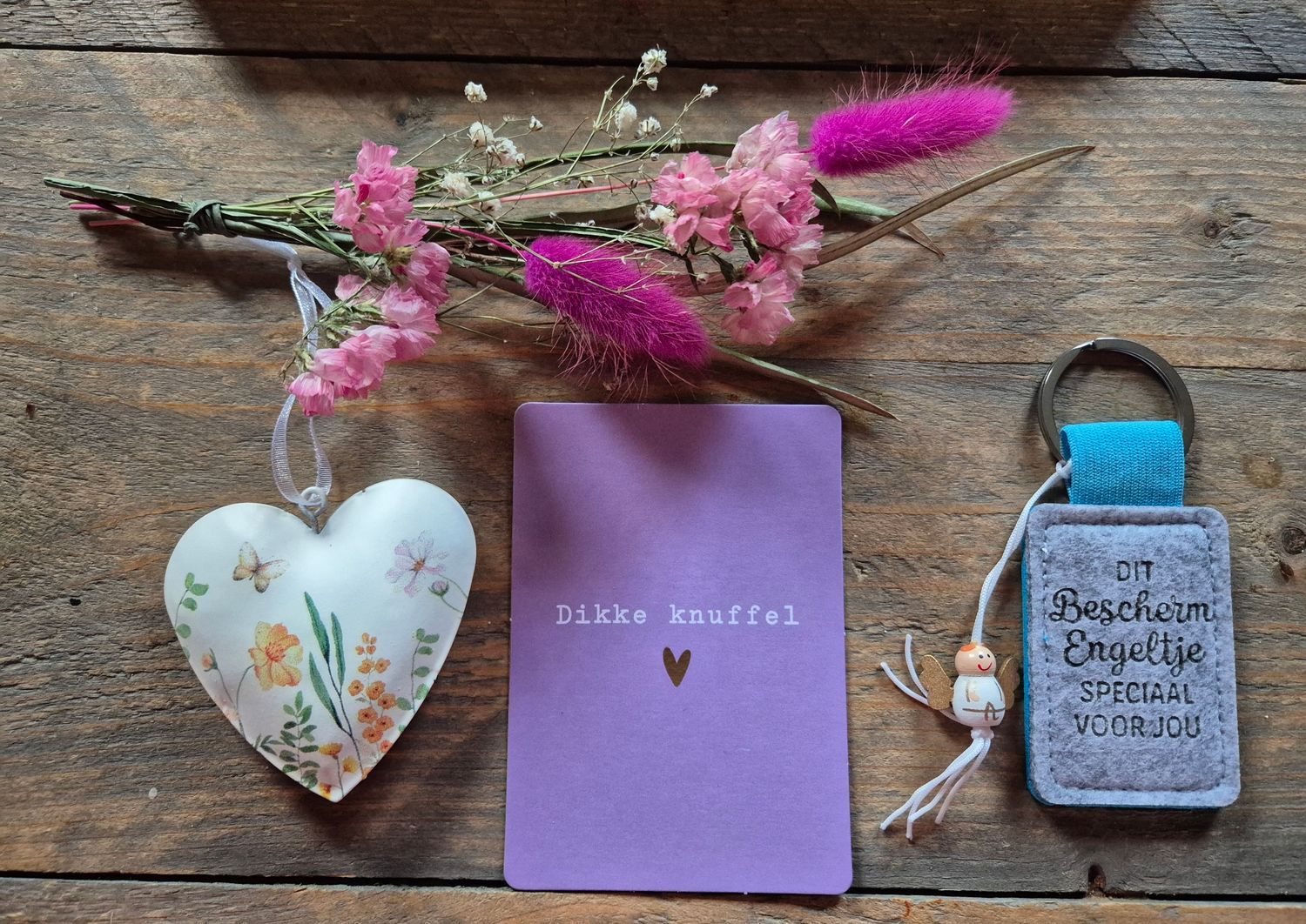 Doos met gedroogde bloemen, een hartvormig ornament, een paarse kaart met een hartje en een sleutelhangertje.