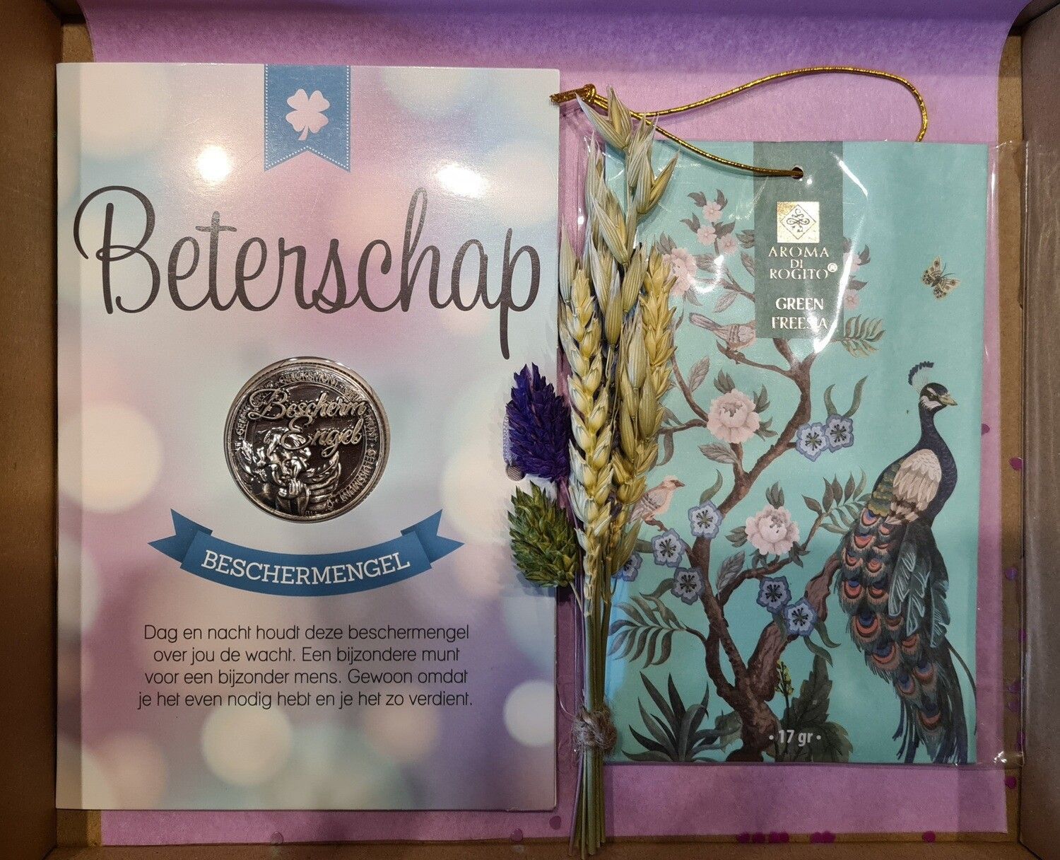 Beterschapscadeaubox met kaart, gedroogde bloemen en een cadeautas met pauwenmotief.