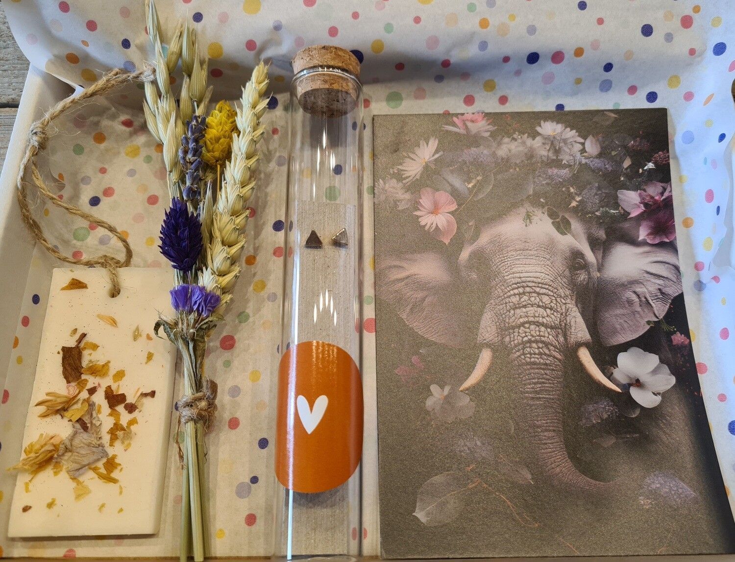 Cadeauverpakking met gedroogde bloemen, een glazen buisje en een ansichtkaart met een olifant.